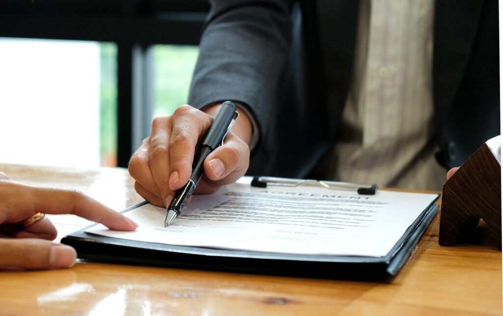 Businessmen selling the house pointing at signing of sale contract.