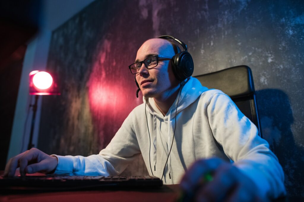 Professional Boy Gamer Plays in Video Game on a eSports Tournament or in Internet Cafe. He Wears